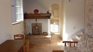 A rustic interior with a wooden dining table, a sofa, a fireplace, and a kitchen area. - Belvilla by OYO Borgo Sanvico Forrest (Corciano)
