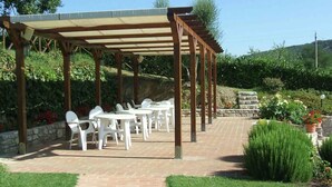 An outdoor patio with tables and chairs, a pergola, and a brick pathway. - Belvilla by OYO Borgo Sanvico Forrest (Corciano)