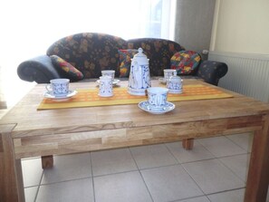 A wooden table with a tea set, including cups, saucers, and a teapot, placed on a mat. - Dyke Space 50 m to the Beach sea (Neuharlingersiel)