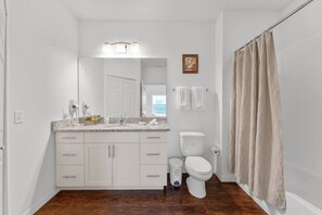 Une salle de bain avec un lavabo blanc, des toilettes et un rideau de douche.