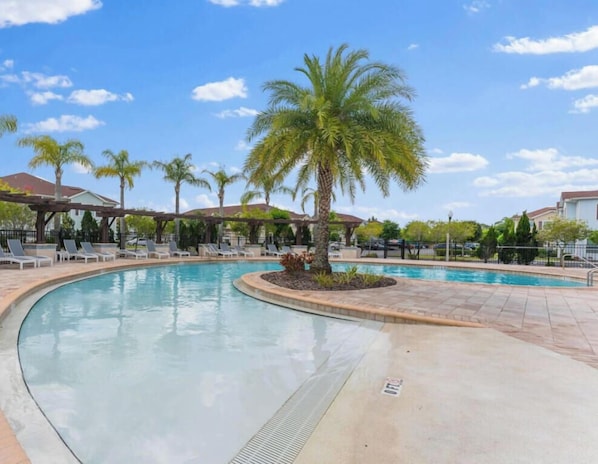 Una piscina con lettini e palme.