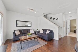 A living room with a sofa set, a coffee table, a patterned rug, and a staircase.