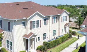 A multi-story residential building with a red roof, white siding, and multiple windows.