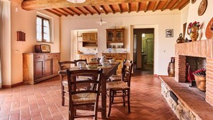 A rustic kitchen with wooden furniture, a brick fireplace, and a tiled floor. - Serene Chianti Retreat (Cavriglia)