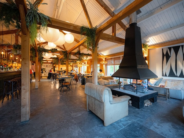 Enjoy a warm and inviting atmosphere in our restaurant, featuring a high ceiling, comfortable seating, and a cozy fireplace.