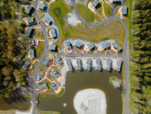 An aerial view of a residential area with multiple houses, a winding road, and a large body of water.