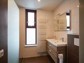 A modern bathroom with a window, a towel rack, a sink, and a mirror. - Zeeland Holiday Home Near Beaches (Heinkenszand)