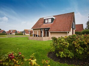 A modern house with a sloped roof, a covered porch, and a well-maintained lawn. - Zeeland Holiday Home Near Beaches (Heinkenszand)