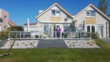 A two-story house with a balcony, a satellite dish, and a paved driveway.