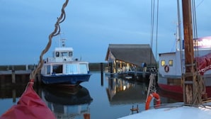 A boat docked at a pier with a building in the background. - Apartment Evening sun (Zingst)