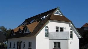 A white building with a steeply pitched roof, multiple windows, and a balcony. - Apartment Evening sun (Zingst)
