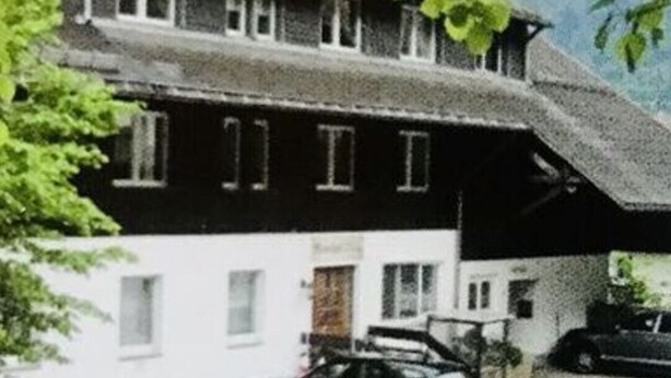 A two-story building with a sloped roof, parked cars in front, and a tree in the foreground. - Meierhof Menzenschwand (St. Blasien)