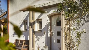 Una casa con techo inclinado, un banco de madera y plantas en macetas.