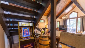 A cozy room with a Pac-Man arcade game, a wooden barrel, a sofa, and a TV.