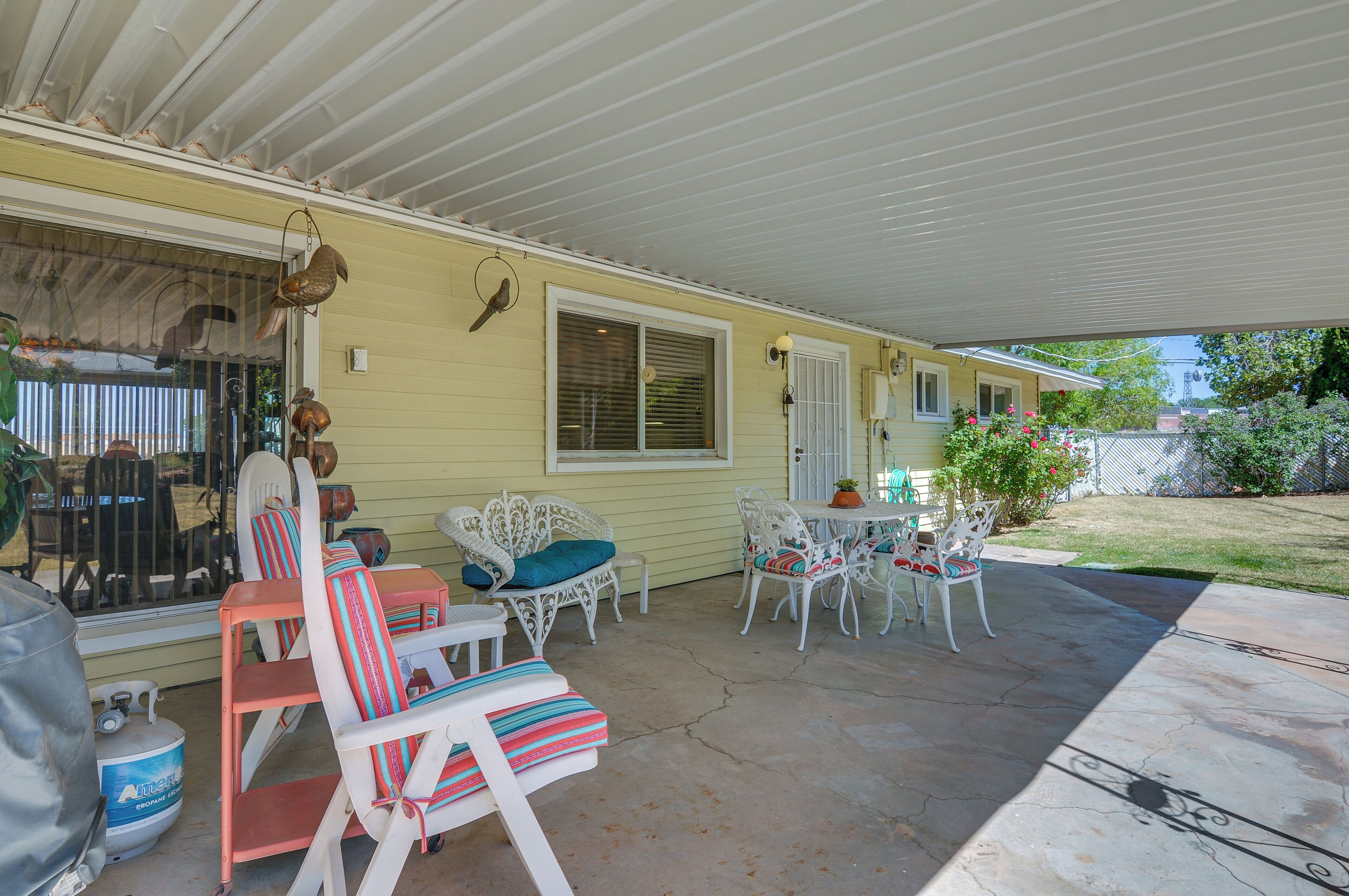 A covered patio with outdoor furniture, a gas tank, and a birdhouse.