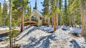 A cabin with a wooden deck and a metal roof, surrounded by snow and trees. - 24-0139 Cabin in Fairplay: Close to Trails! (Fairplay)