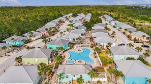 A resort with multiple bungalow-style houses arranged around a central swimming pool. - "It's 5:00 Here" The Rookery III sleeps 10 (Gulf Shores)
