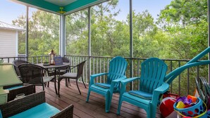 A covered outdoor area with a table and chairs, a sign, and a view of trees.