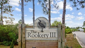 A wooden sign with a bird and the text "The Rookery III" indicating a property name.