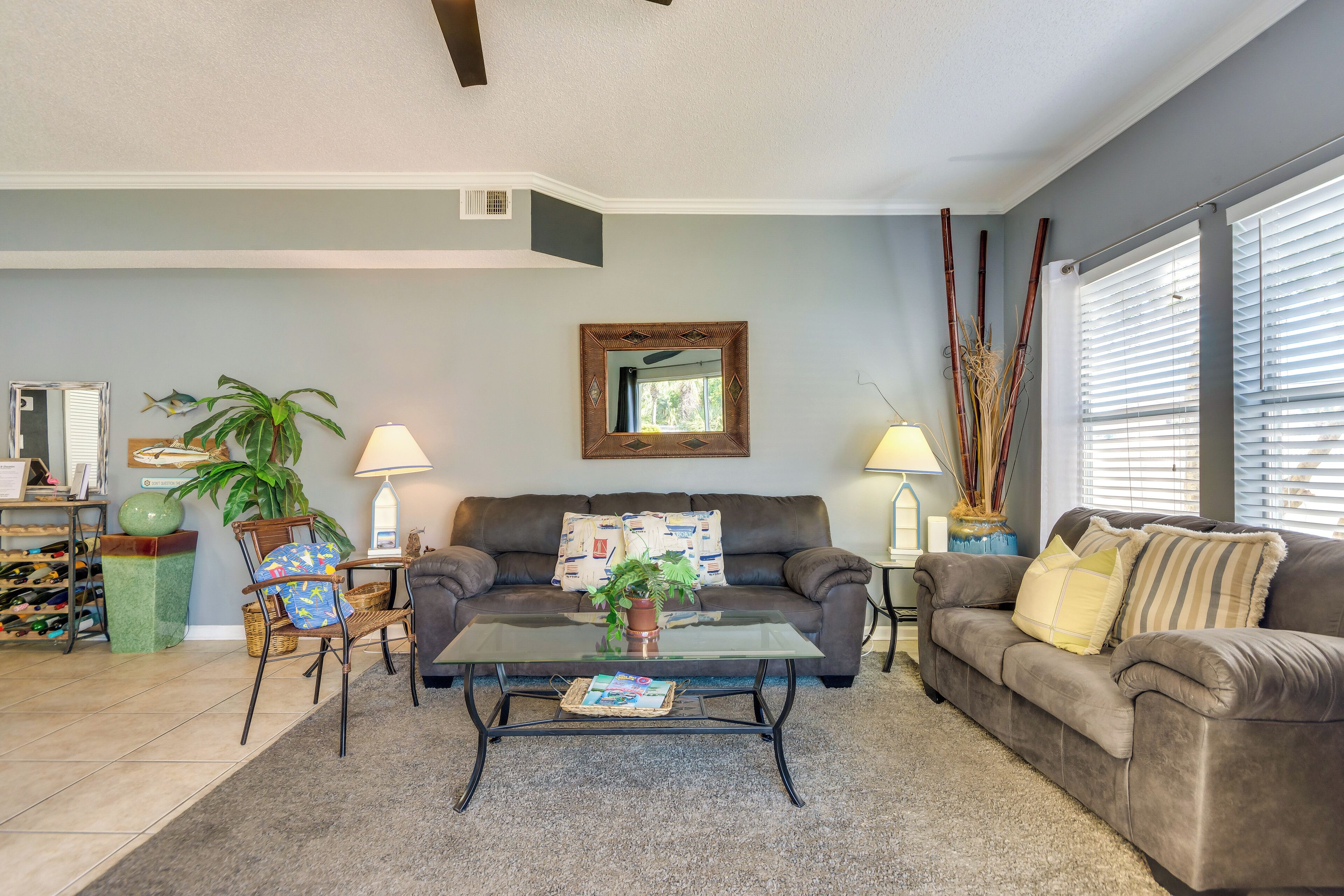 A living room with a brown couch, a glass coffee table, and a potted plant.