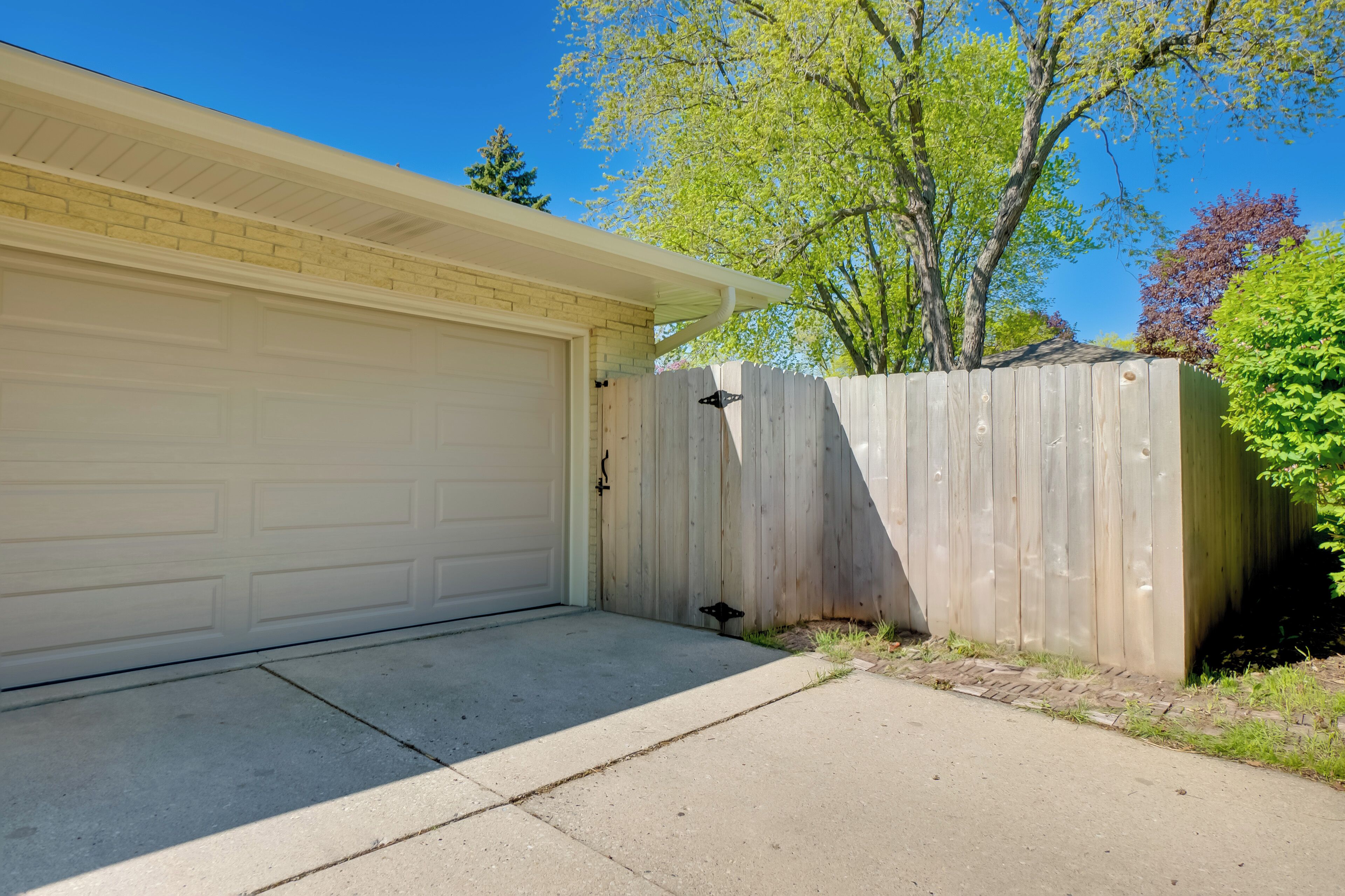 A garage with a white door, a wooden fence, and a clear blue sky.