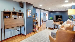 A modern living room with a wooden entertainment unit, a sofa, a coffee table, and a TV. - Cozy Milwaukee Apartment w/ Deck, 2 Mi to Airport! (Milwaukee)