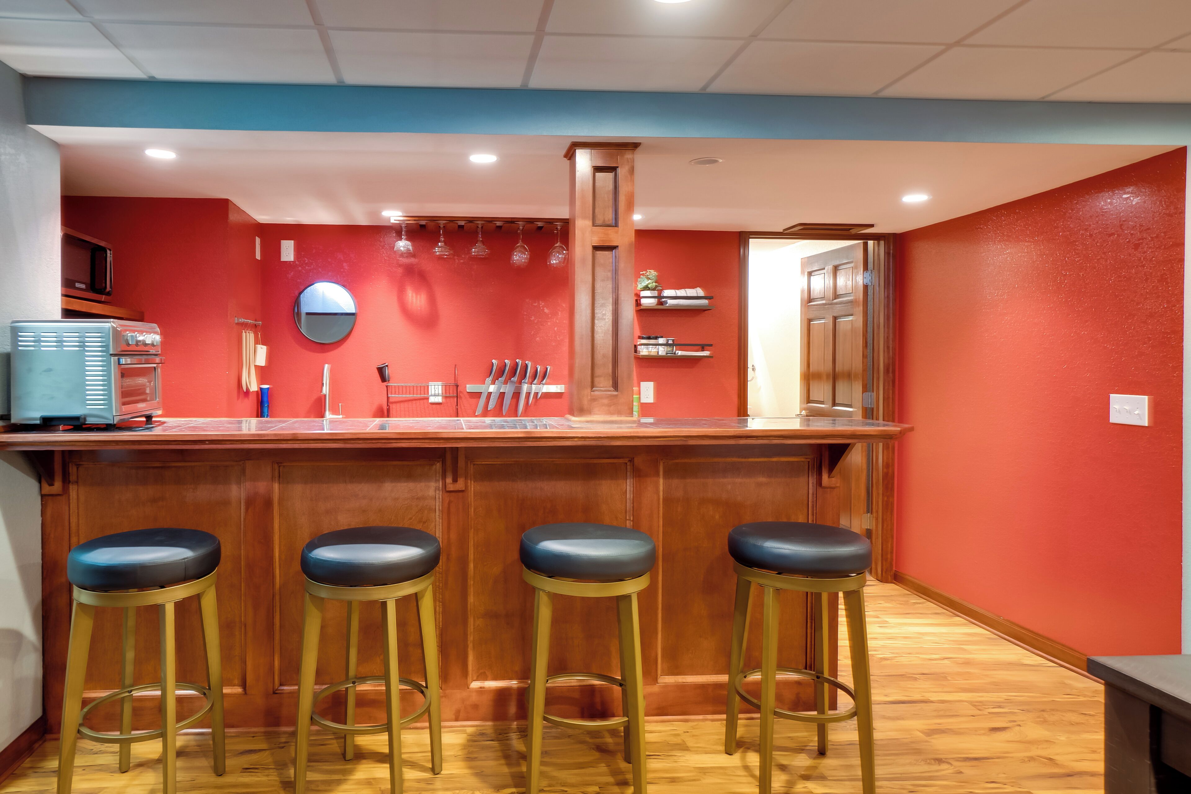 A bar area with wooden stools, a counter, and a red wall.