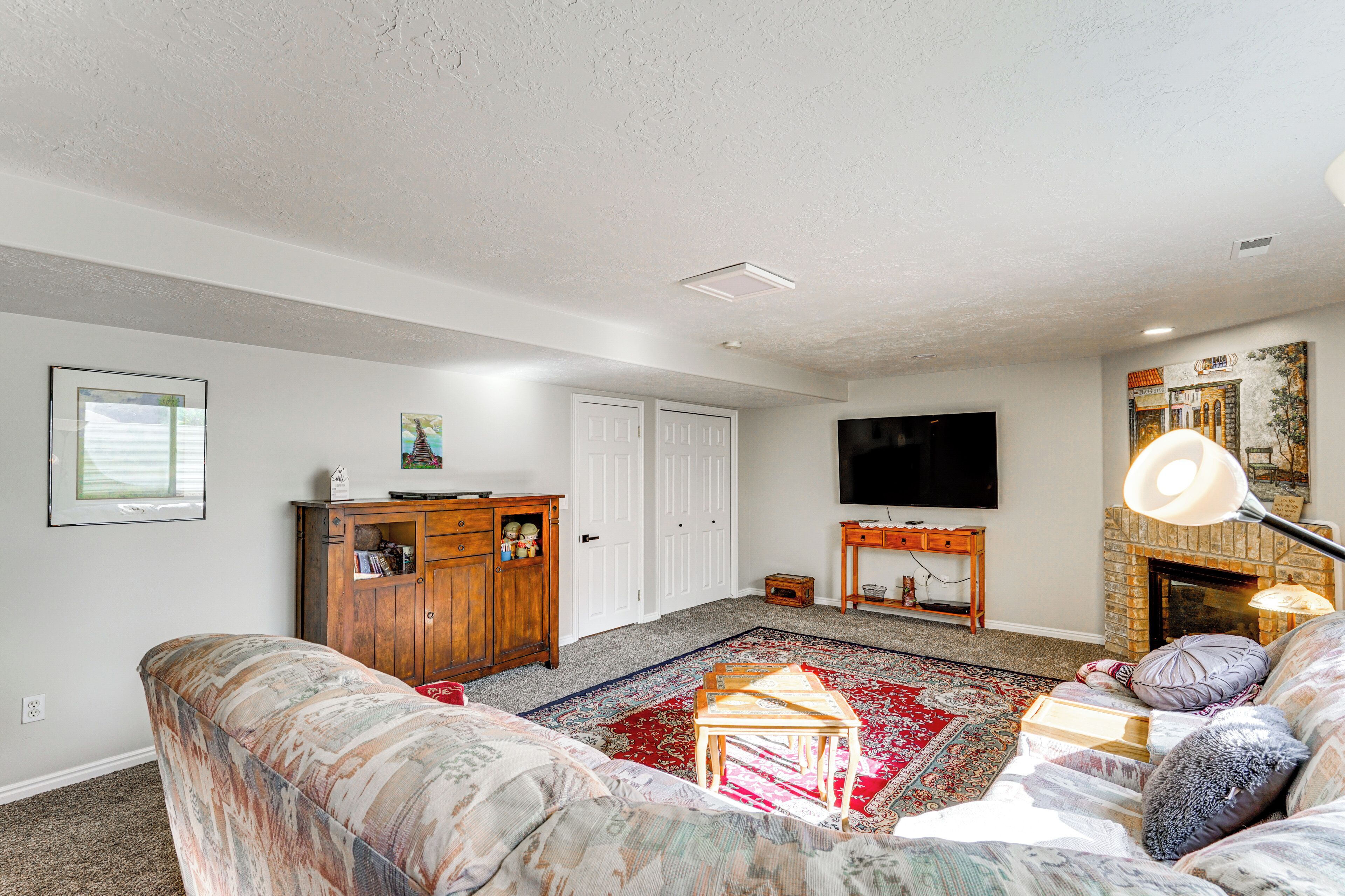 A living room with a sofa, a wooden cabinet, a television, a fireplace, and a patterned rug.