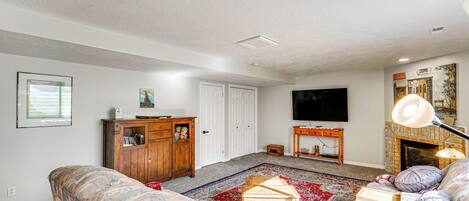 A living room with a sofa, a wooden cabinet, a television, a fireplace, and a patterned rug.