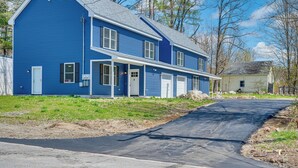 Ein blaues Haus mit zwei Stockwerken, einer Veranda, einer Garage und einer Auffahrt zu einer Straße.