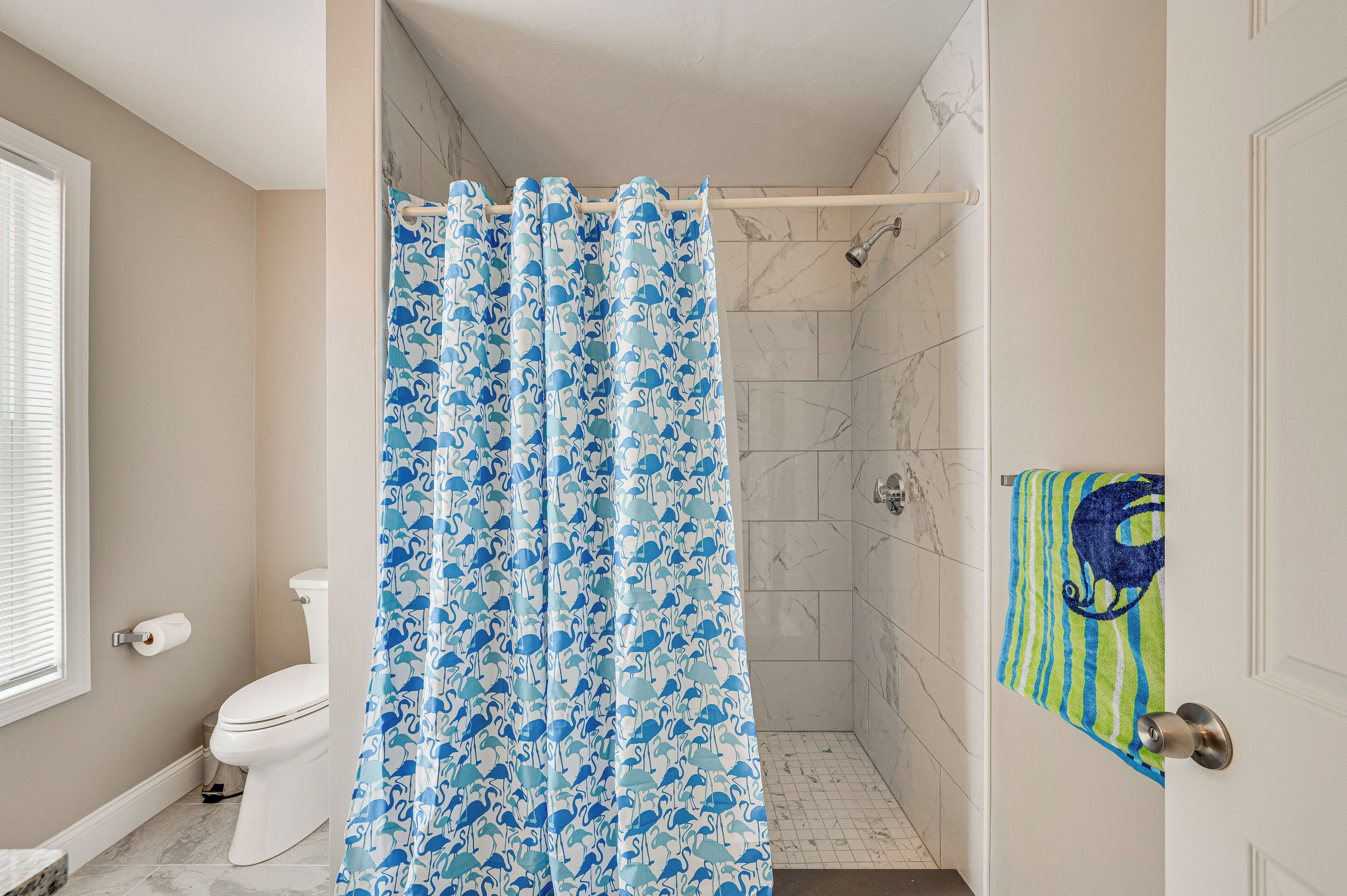 A bathroom with a shower curtain, toilet, and a towel rack with a towel.