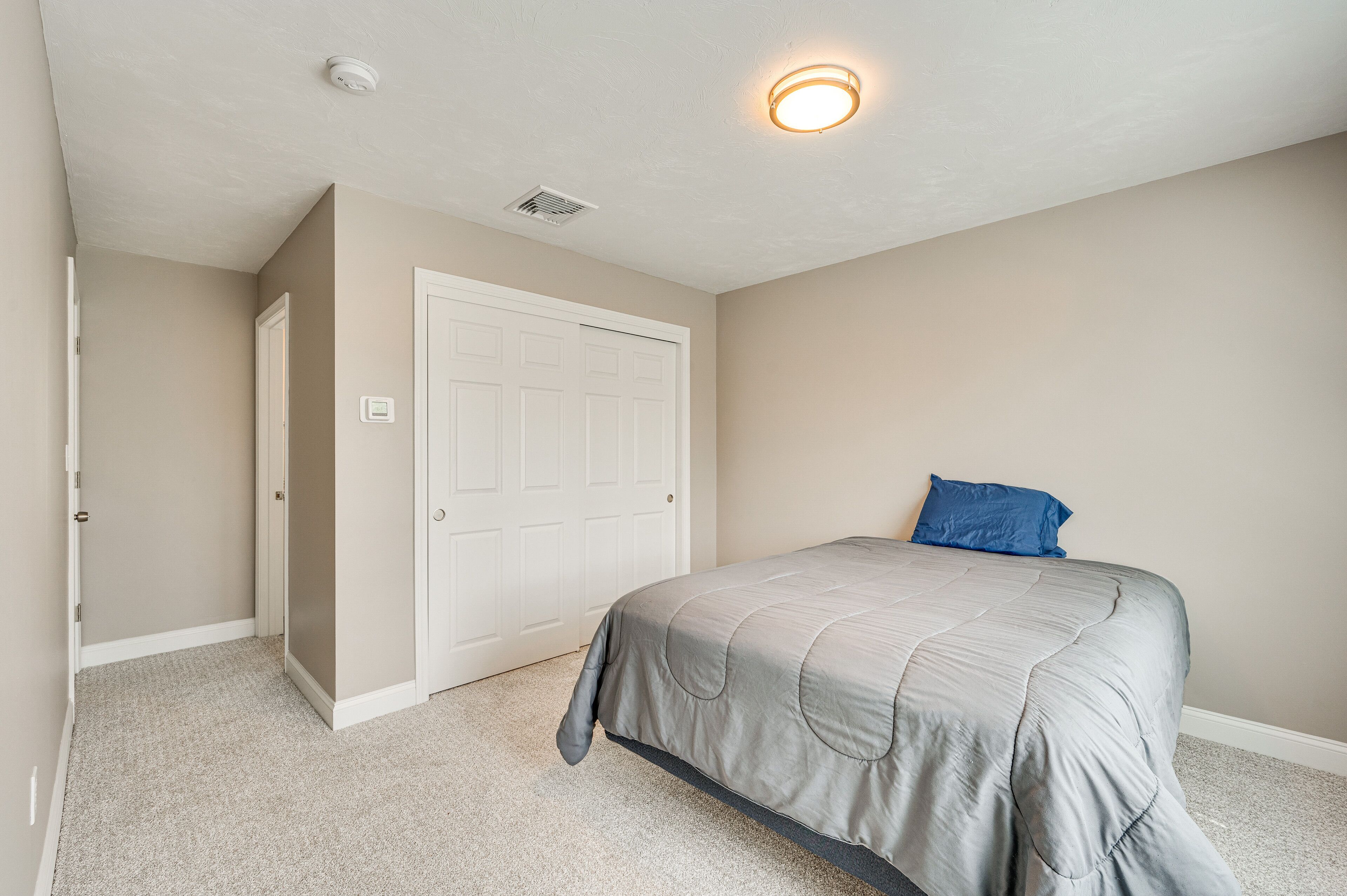 A bedroom with a bed, a door, and a ceiling light.