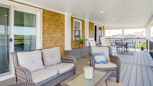 A covered outdoor area with wicker furniture, a glass table, and potted plants. - Unique Tangier Cottage w/ Chesapeake Bay Views! (Tangier)