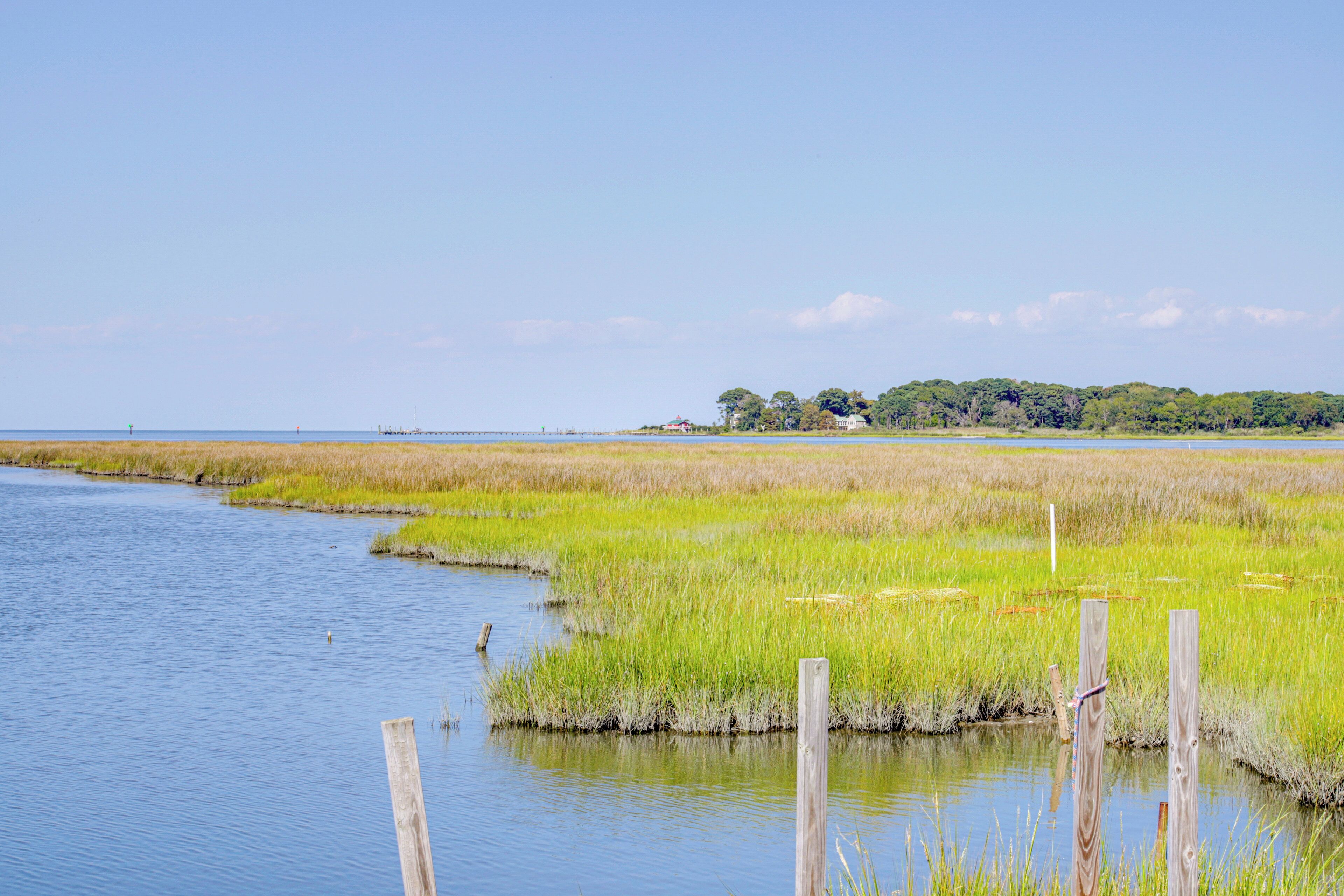 A calm river with grassy banks and a distant house.