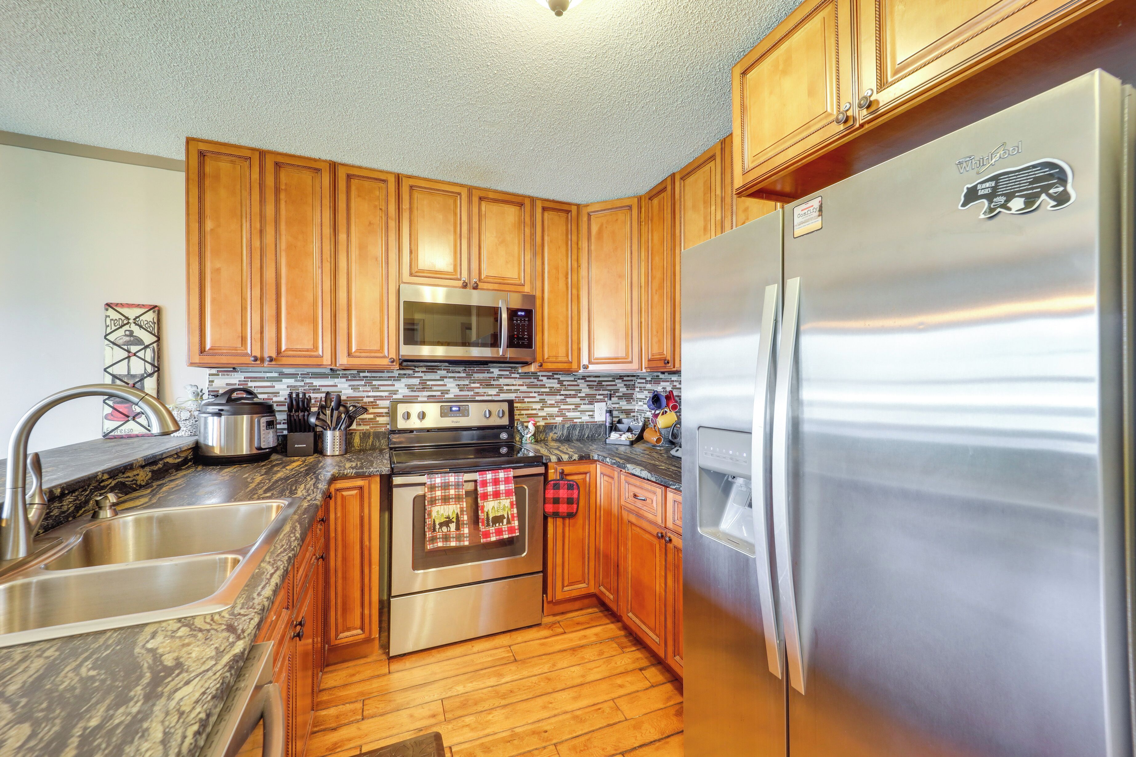 A kitchen with wooden cabinets, stainless steel appliances, a granite countertop, and a stainless steel refrigerator.
