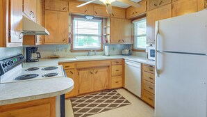 A kitchen with wooden cabinets, a white stove, a ceiling fan, and a refrigerator. - Walk to Restaurants: Stockton Home w/ Game Room (Stockton)