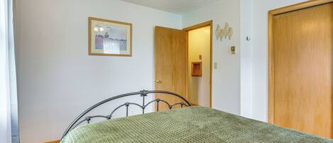 Un dormitorio con una cama, un ventilador de techo, una puerta de madera y un cuadro enmarcado en la pared.