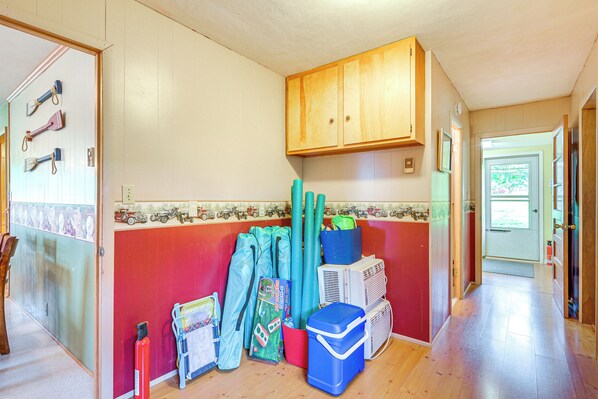 A hallway with a wooden cabinet, a red wall, and various items like bags and a cooler. - Walk to Restaurants: Stockton Home w/ Game Room (Stockton)