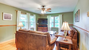 A living room with a brown leather sofa, a wooden coffee table, and a ceiling fan. - Walk to Restaurants: Stockton Home w/ Game Room (Stockton)