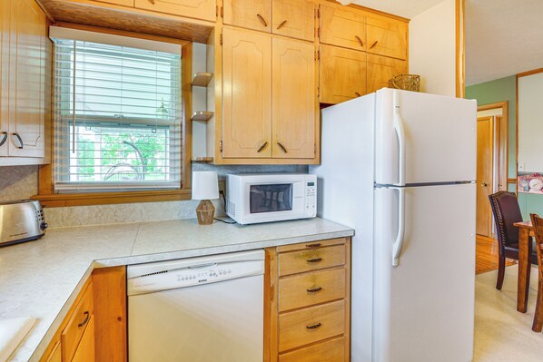 A kitchen with wooden cabinets, a microwave, a refrigerator, and a dishwasher. - Walk to Restaurants: Stockton Home w/ Game Room (Stockton)