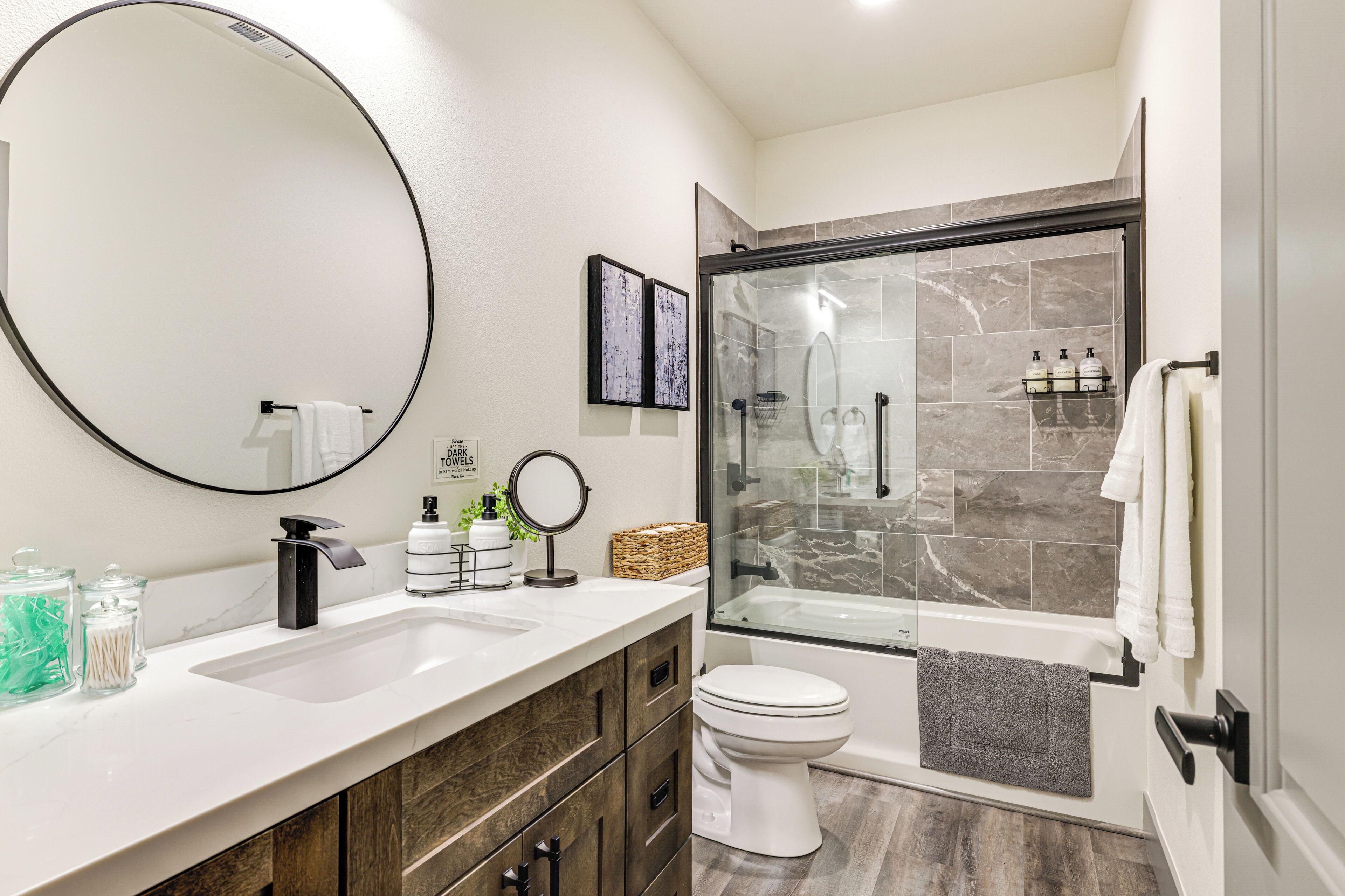 A modern bathroom with a large mirror, a sink, a toilet, and a glass-enclosed shower area.