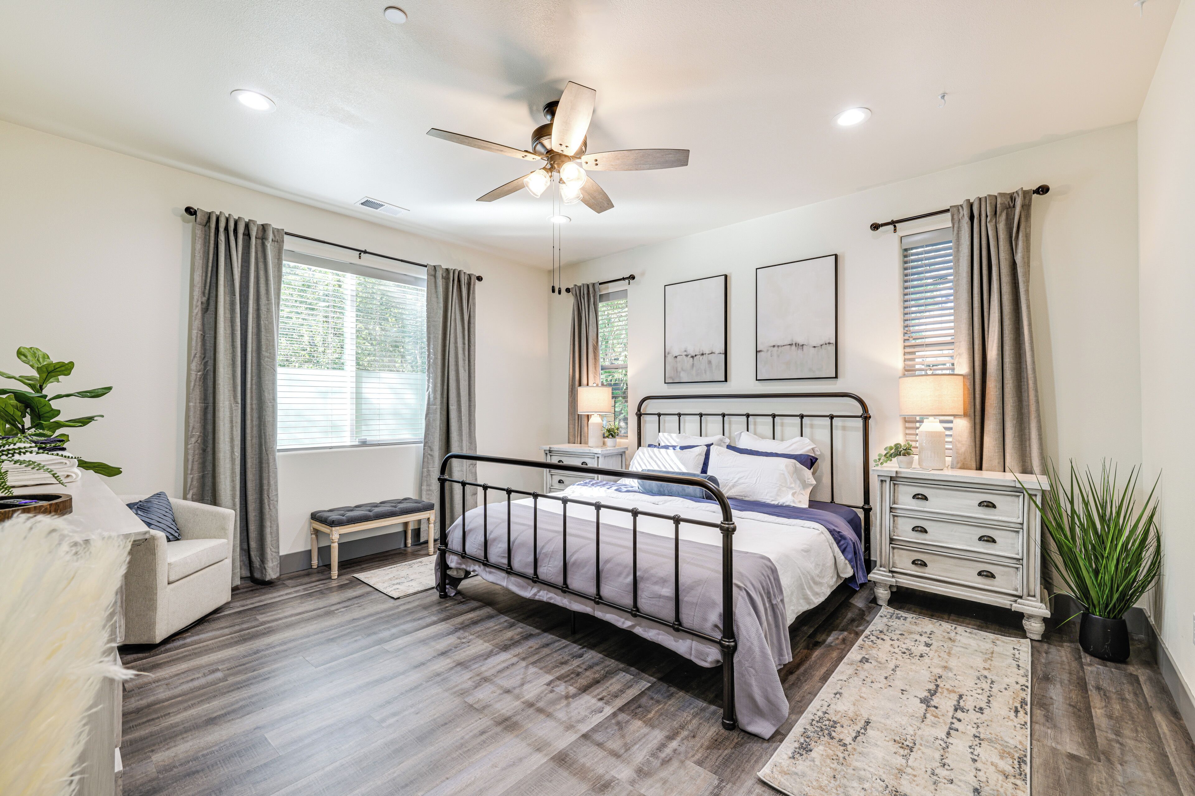 A bedroom with a bed, bedside tables, a ceiling fan, and a window with curtains.