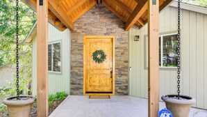 A wooden door with a wreath, a stone wall, and a porch with wooden beams. - Game Room & Patio: Picturesque Home in Sonora (Sonora)