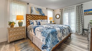 Une chambre à coucher avec un lit, des tables de chevet, une commode et un tableau au mur.