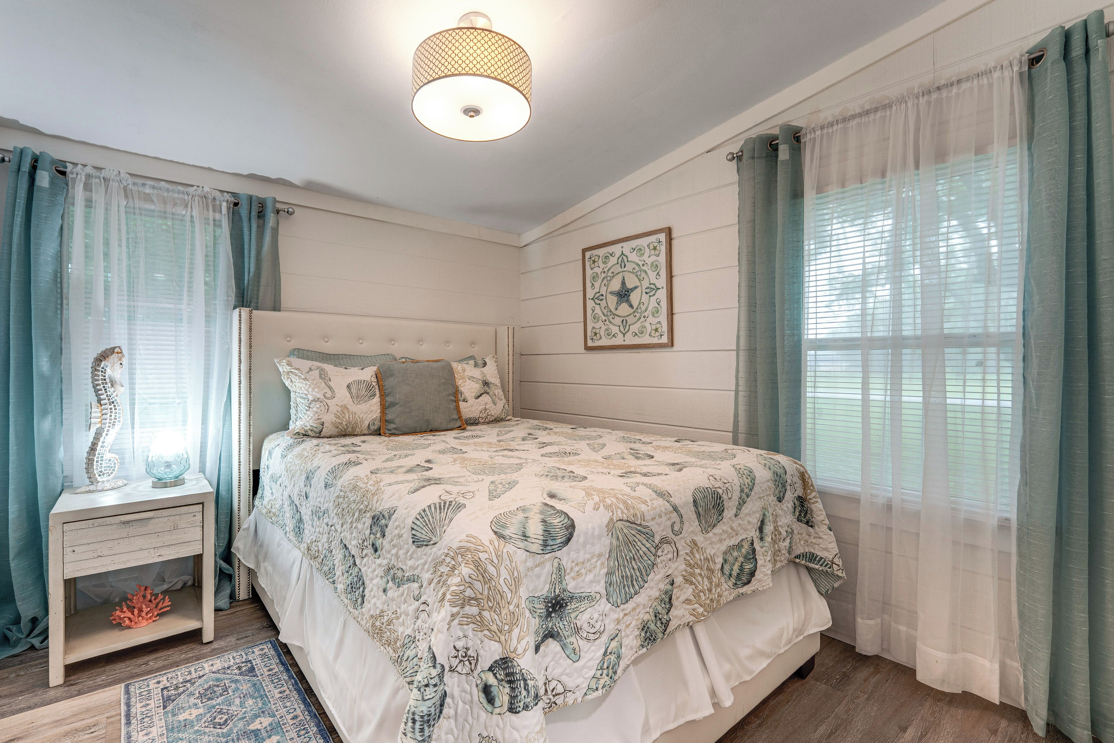 A bedroom with a bed, bedside table, and a nightstand with a lamp.