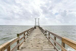 A wooden pier extending into a body of water under a cloudy sky. - Walk to Boat Ramp: Newly Remodeled Seadrift Home! (Seadrift)