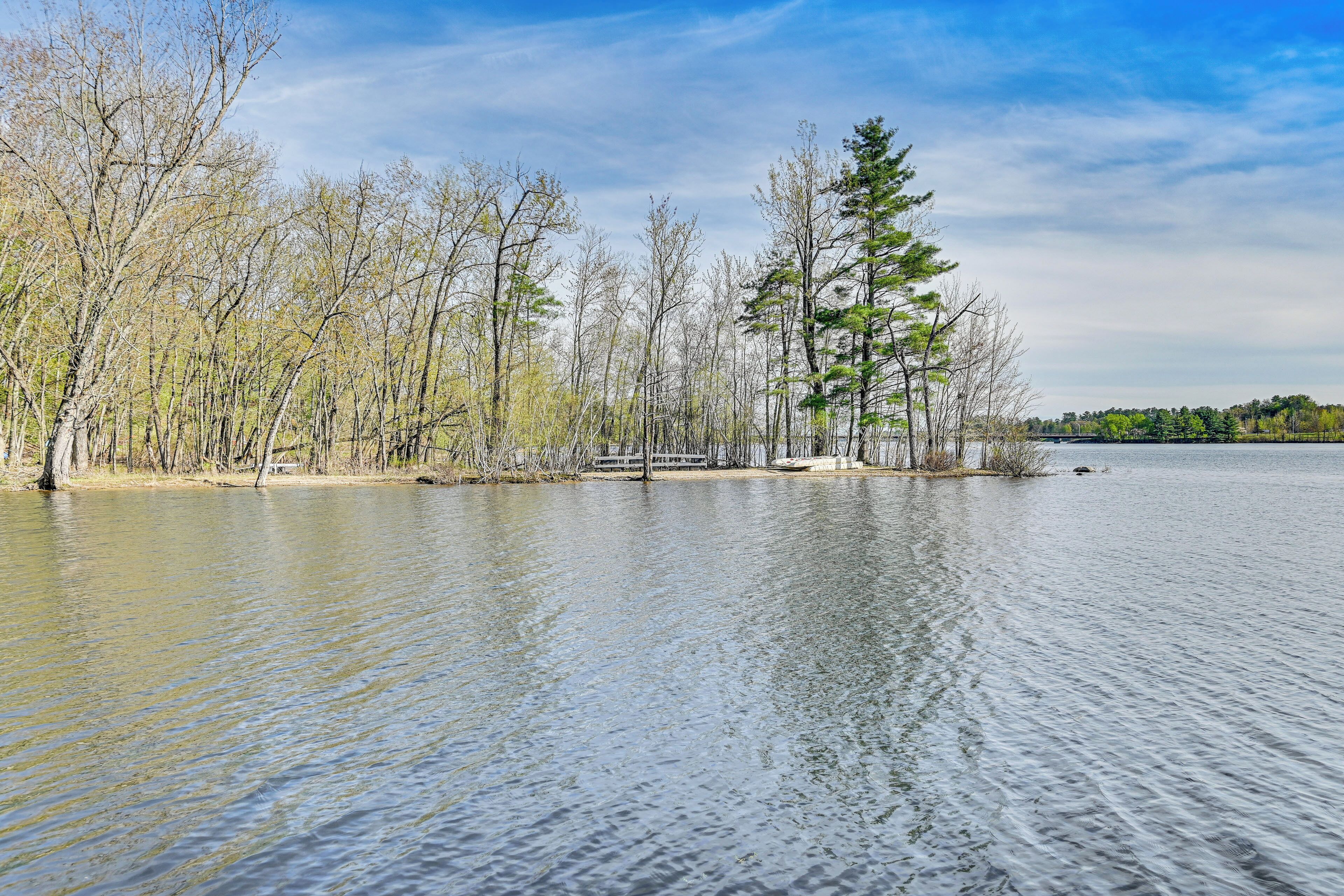 A calm lake with trees and a wooden dock.