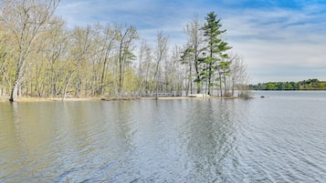 A calm lake with trees and a wooden dock.