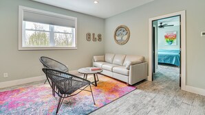 A modern living room with a white sofa, black wireframe chair, and a colorful rug. - Fire Pit + Beach Access: Quiet Northville Retreat (Northville)