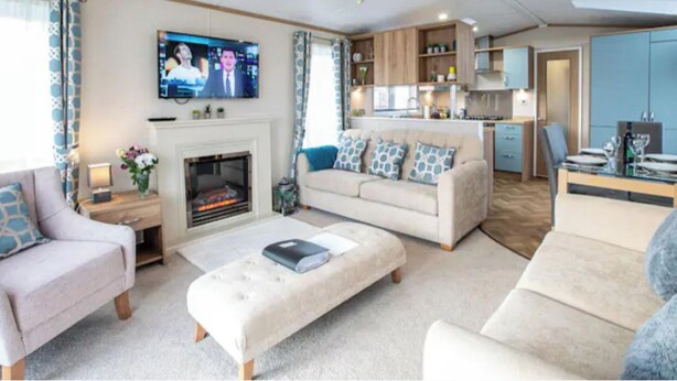 A living room with a fireplace, a television, and a kitchenette in the background. - 3-bed Lodge Sleeps 6 - Private Hot tub - Resort (St. Andrews)